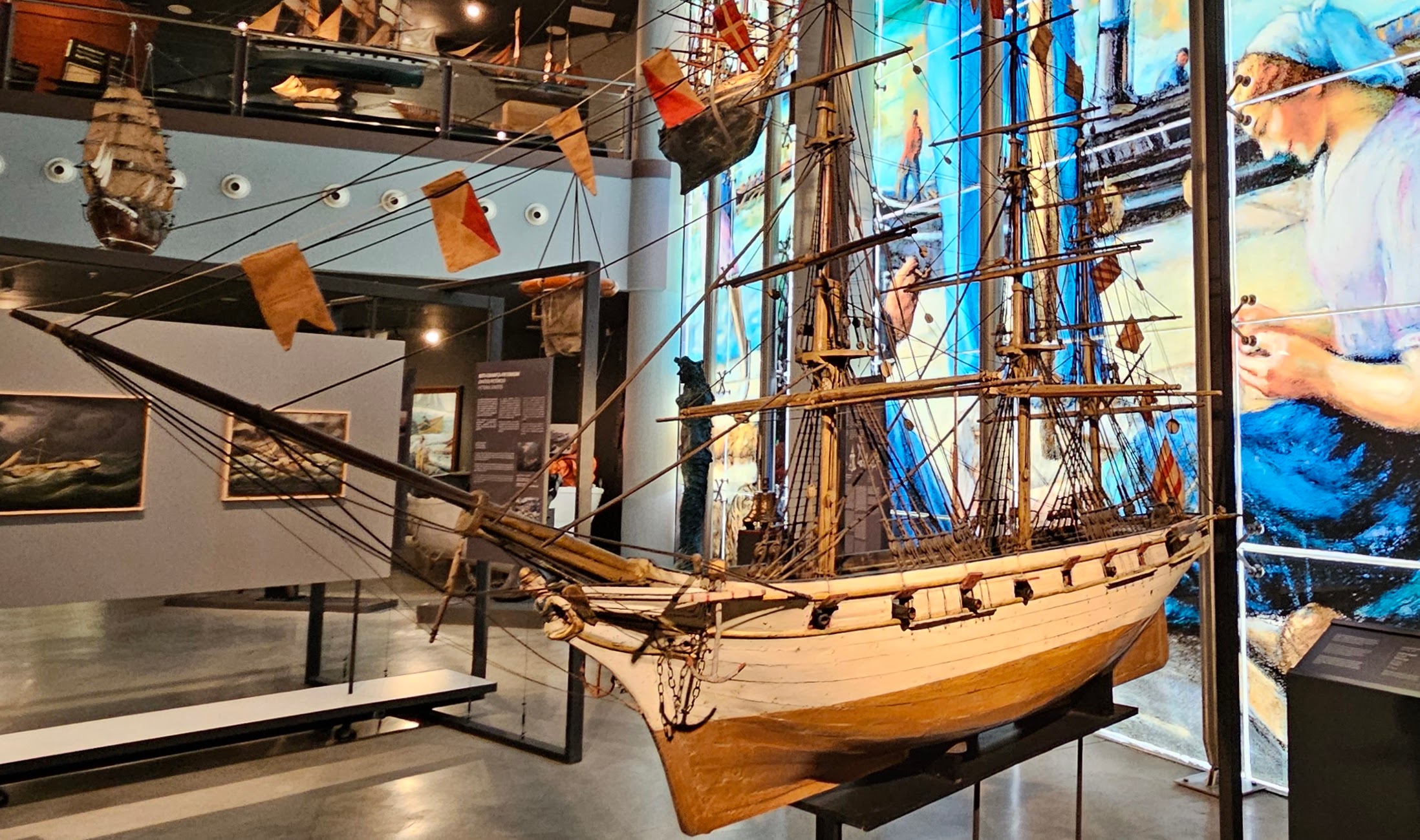 Ship replica with glass mural and other museum displays in background