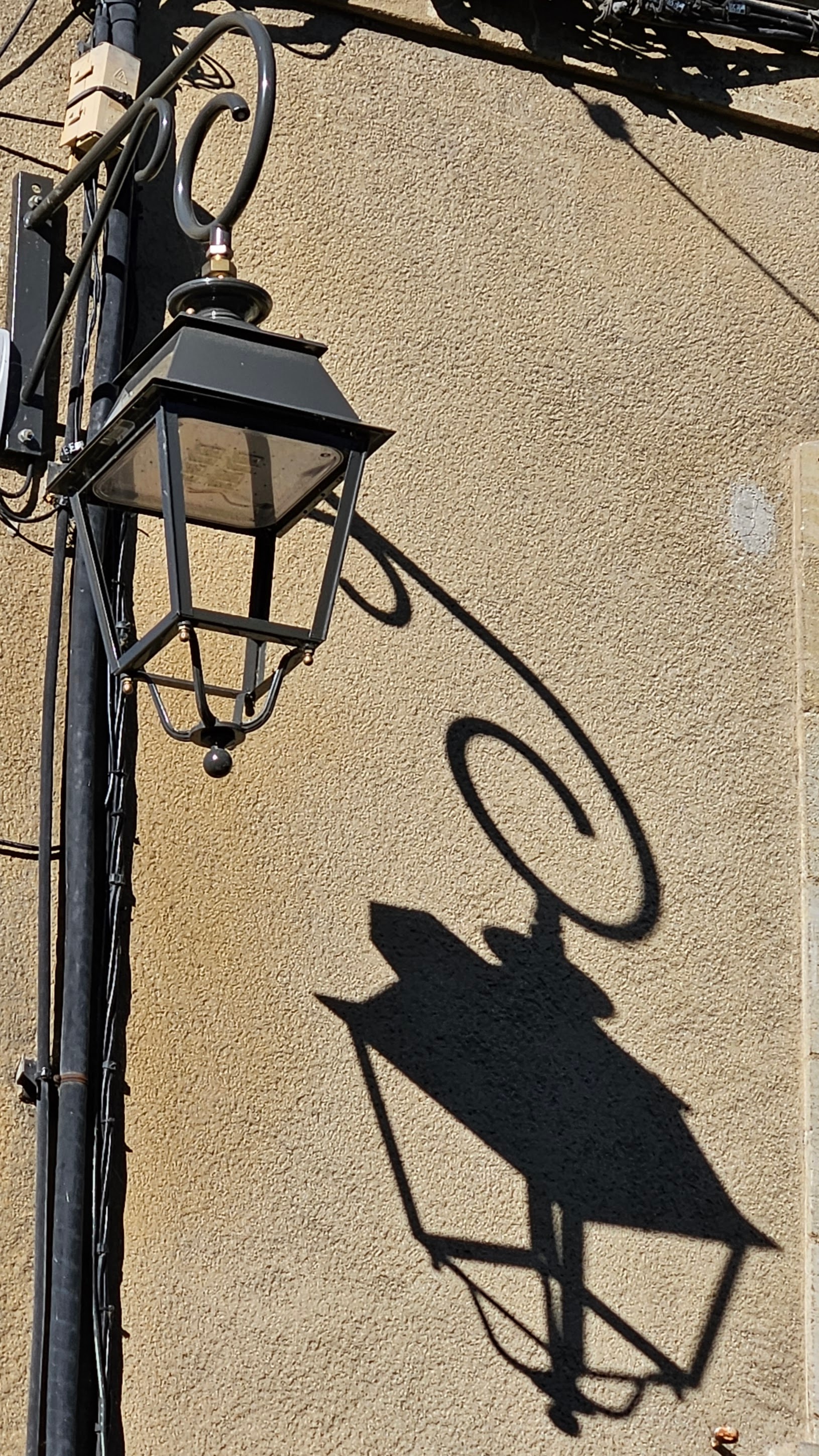 Lamp and its shadow against a stucco wall 
