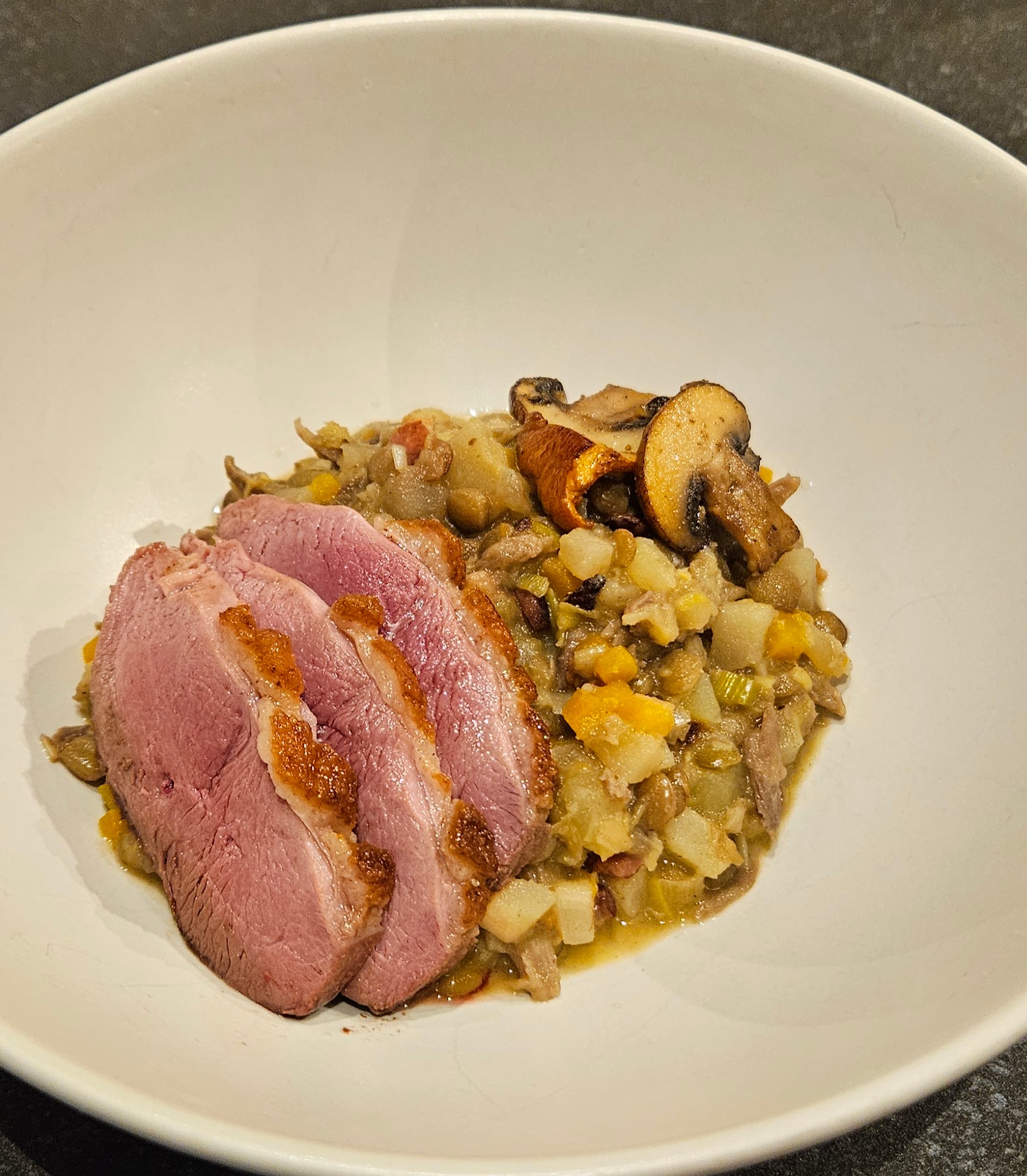 Vegetable, lentil, and duck ragout, topped with sliced duck breast and browned mushrooms
