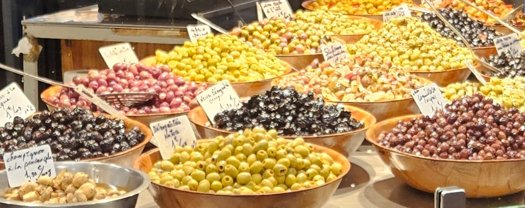 Bowls of different kinds of olives at a counter in the market
